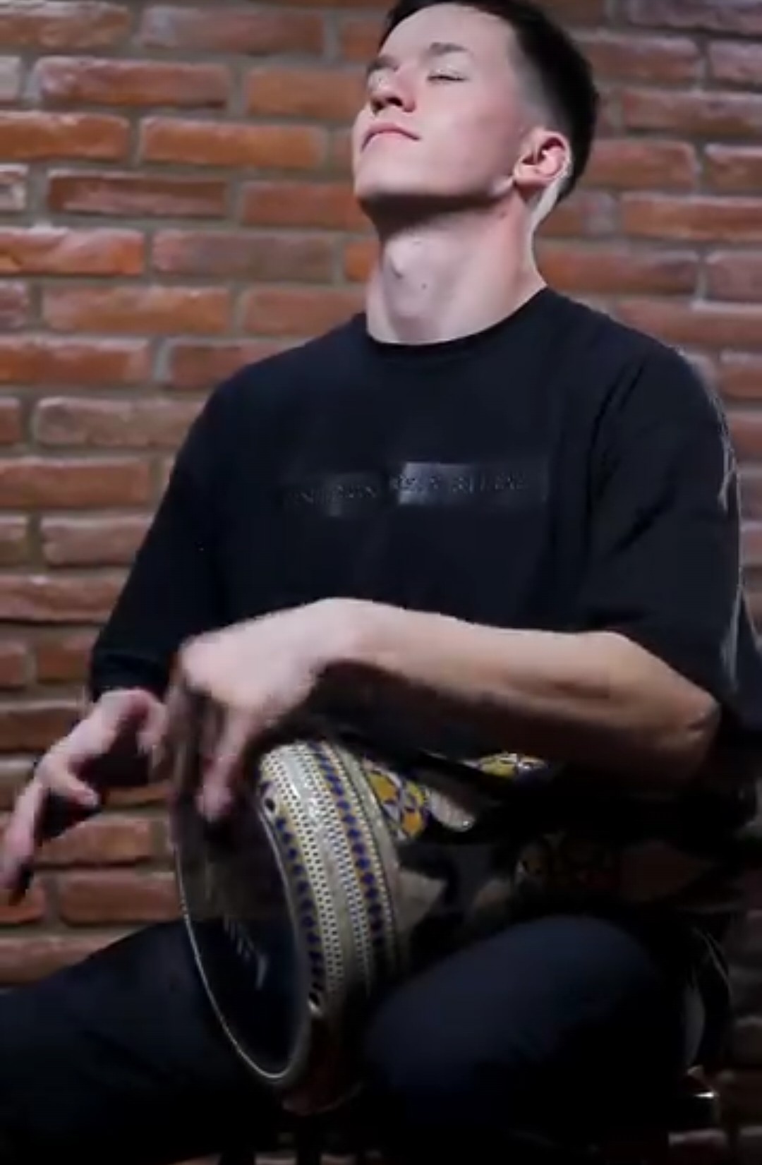 Lucas Cortese tocando el derbake sentado, con los ojos cerrados
