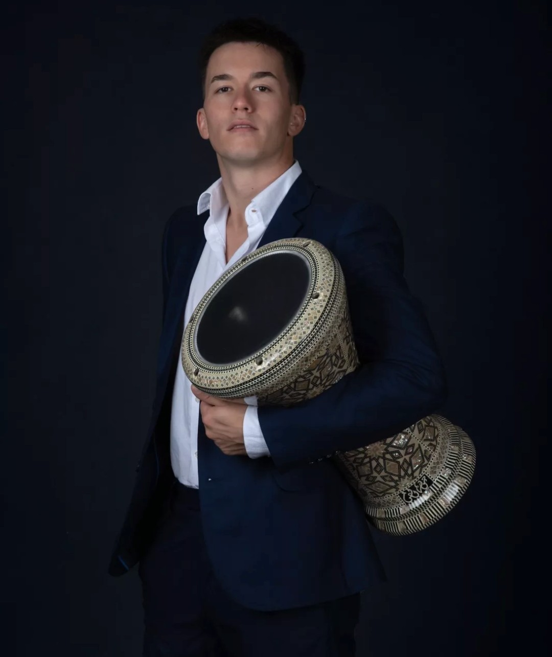 Lucas Cortese de traje, sosteniendo su derbake